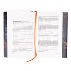 Der Text beginnt mit „DER HIMMEL FÄRBTE sich allmählich orange.“ Ein Buch mit offenem Text und einem orangenen Leseband.