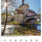 Altes Rathaus Bamberg. Fachwerkbau auf Brücke. Sonniger Tag, Wasser fließt darunter. Zweige rahmen das Gebäude ein.