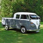 Nummernschild mit Text "WN-NC 914". Ein klassischer, grauer VW-Transporter auf einer grünen Wiese vor Bäumen.