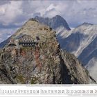 Kalender für März. Bergpanorama mit Berghütte auf Felsspitze. Im Hintergrund hohe, felsige Berge unter bewölktem Himmel.