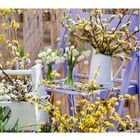 03 steht oben rechts. Darunter ein Kalender. Links Frühlingsblumenarrangement mit gelben und weißen Blüten.