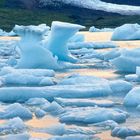 Kalender: 03, 01-31. Eisberge schwimmen im Wasser, im Hintergrund schneebedeckte Berge bei Sonnenuntergang.