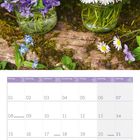 Kalender für März 2027. Oberhalb: Veilchen und Gänseblümchen in Gläsern auf Holz.