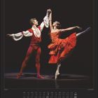 März | March. Zwei Tänzer in eleganter Pose, er trägt Rot, sie ein rotes Kleid, beide in dynamischer Bewegung auf der Bühne.