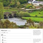 Kalenderseite für Mai/Juni mit Zwillingszeichen. Bild: Grüne Landschaft mit Brücke, Fluss und Häusern.