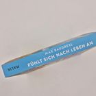 Ein Buchrücken mit blauem Hintergrund zeigt den Text: "MAX BAUDREXL FÜHLT SICH NACH LEBEN AN".