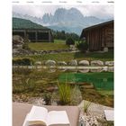 "September 20-26, Cyprianerhof, Italy." Ein offenes Buch liegt auf einer Liege vor einem Teich in alpiner Landschaft.