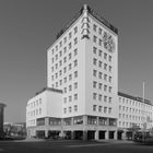 Am oberen Rand steht "SPARKASSE". Ein großer, heller Turm mit vielen Fenstern und einer Uhr an der Fassade.