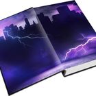 Ein aufgeschlagenes Buch zeigt eine Illustration einer Skyline mit Blitzen in lila und dunklen Farbtönen.