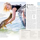 Links der Text: "Ein guter Fang", rechts "Sie hat Biss". Frau hält im Boot einen großen Fisch über dem Wasser.