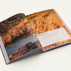 Der Text im Buch lautet: "Gedanken und Impulse für Juli." Gezeigt werden rote Felsen und ein ruhiges Gewässer.