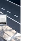 Text: "No.115 2006 19". Eine leere Werbetafel an einer Straße, die schattig ist, mit Zebrastreifen und Bürgersteig.