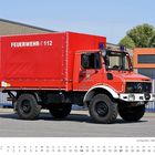 "FEUERWEHR 112" in Weiß auf rotem LKW. "Freiwillige Feuerwehr Stadt Wasserburg" mit Logo auf Tür. Hintergrund: Gebäude.