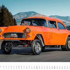"März", Monatskalender mit nostalgischem, orangefarbenem 1955er Chevrolet 210 vor Bergkulisse.