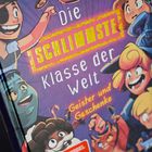 Text: "Die schlimmste Klasse der Welt: Geister und Geschenke." Comic-Illustration: fröhliche Kinder, bunte und lebendige Szenen.