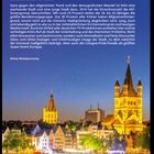 "Willkommen in Köln. Kölner Rhepanorama." Unter einem blauen Himmel sind abends beleuchtete historische Gebäude.