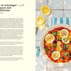 „Klippfisch in würziger Tomatensauce mit Kapern & Zitrone“ – Teller mit Fisch in roter Sauce, Zitronenscheiben und Kräutern.