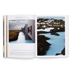 Island: A Mineral-Rich Geothermal Lagoon. Links ein Betongebäude am türkisblauen Wasser, rechts schneebedeckte Felsen.
