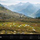 Südtirol. Kalender mit einem Bergpanorama. Ein geschwungener Bach schlängelt sich durch eine grüne, bergige Landschaft.