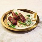 Mehrere Leute in einem Gewürzladen. Eine Frau hält eine Süßigkeit aus Nüssen und Pistazien.