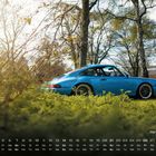 "Porsche 964", darunter Kalenderdaten. Blaues Auto in einer grünen Landschaft, Bäume im Hintergrund.