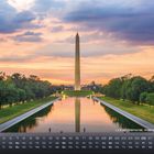 „Lincoln Memorial, Washington D.C.“. Ein Obelisk spiegelt sich in einem Wasserbecken, von Bäumen umgeben, bei Sonnenuntergang.