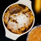 Ein weißes Keramikschälchen mit Kaiserschmarrn, bestreut mit Puderzucker. Daneben eine Schale mit Apfelmus.