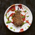 Keine erkennbaren Texte. Ein paniertes, längliches Gemüse auf einem weißen Teller mit roter und grüner Soße.