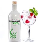 Aufschrift: "German Dry Gin MOMENTUM Holy Basil". Flasche mit Holzverschluss; Glas mit Eis, Himbeeren, Basilikum.