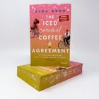 Auf einem Buchcover steht: Kyra Groh - The Iced Caramel Coffee Agreement. Illustration: Zwei Personen auf Fahrrädern.