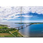 Seite 3 zeigt eine weitläufige Landschaft mit einer Brücke über blaues Wasser unter leicht bewölktem Himmel.