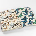 Eine offene Zeitschrift zeigt bunte Schmetterlinge auf zwei Seiten. Links orange und schwarz, rechts grün und blau.