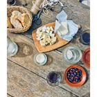 Seite 30. Ein Rustikaltisch mit Brot, Käse, Oliven, Kerze und Getränken neben einer Schere und Schnur.