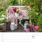"Juli 2027, 27. Woche. Gartenbank mit Decke, Blumentopf mit bunten Rosen, von Büschen umgeben. Kalenderlayout darunter."