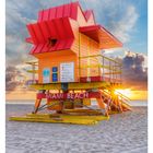 "MIAMI BEACH" steht auf einem farbenfrohen Rettungsschwimmerturm am Strand während eines Sonnenuntergangs.