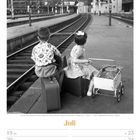 Juli 19 Mo, 20 Di, 21 Mi, 22 Do, 23 Fr, 24 Sa, 25 So, KW29/2027. Zwei Kinder am Bahnhof mit Koffern schauend auf Gleise.