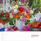 Juli/August 2027, 30. Woche. Ein bunter Blumenstrauß in einer Vase, umgeben von Früchten und einer Teekanne.