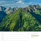 30. Woche, Juli/August 2027. Grün bewachsene Berglandschaft unter blauem Himmel.