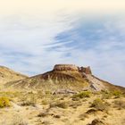 Text: "KARAKALPAKSTAN UND DER ARALSEE". Wüstenlandschaft mit Hügeln, spärlicher Vegetation und Ruinen im Hintergrund.