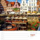 34. Woche, August 2027. Historische Gebäude mit Fachwerk und Cafés am Wasser.