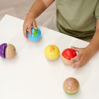 Kind spielt mit bunten Holzkugeln auf einem weißen Tisch. Gedruckte Tiermotive auf den Kugeln.