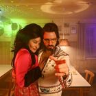 Zwei Personen in bunter Retro-Kleidung, umarmen sich freundlich, darunter eine glitzernde Diskokugel im Hintergrund.