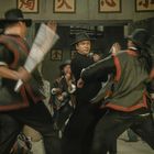Mehrere asiatische Schriftzeichen oben, darunter Männer in einem Kampf in traditioneller Kleidung und Hüten.
