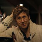 Eine Person mit Brille in einem gemütlichen Pullover lehnt an einer Bar, daneben steht eine Bierflasche.