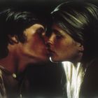 Zwei Menschen küssen sich zärtlich, Stirn an Stirn, in einem dunklen Hintergrund.