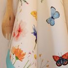 Keine Texte vorhanden. Eine Illustration zeigt bunte Blumen und Schmetterlinge auf einem Stoff mit hölzernem Küchenbesteck.