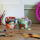 "Viva la Vida" steht auf einer der beiden Tassen. Die Tassen sind bunt bemalt mit Frida Kahlo und Tieren. Malerutensilien umgeben sie.