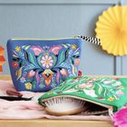 Bunte, florale Designs auf blauer und grüner Kosmetiktasche, daneben eine Haarbürste und ein Lippenstift.