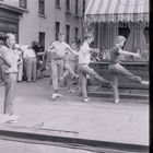 "Madelain" auf einem Sonnenverdeck; vier tanzende Männer neben einem Mann mit Megafon auf einer Straße.