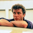 Ich kann diesen nicht identifizieren, aber es ist ein Mann, der über die Arme gelehnt nachdenklich schaut.